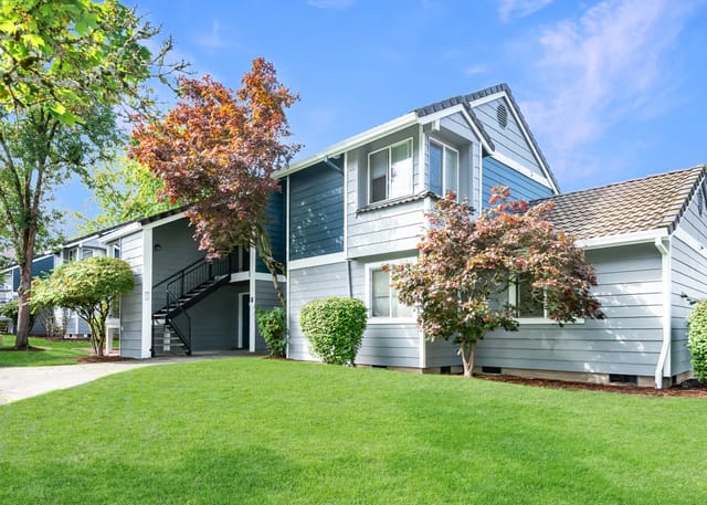 Exterior view of apartment buildings with lush green lawns and trees.