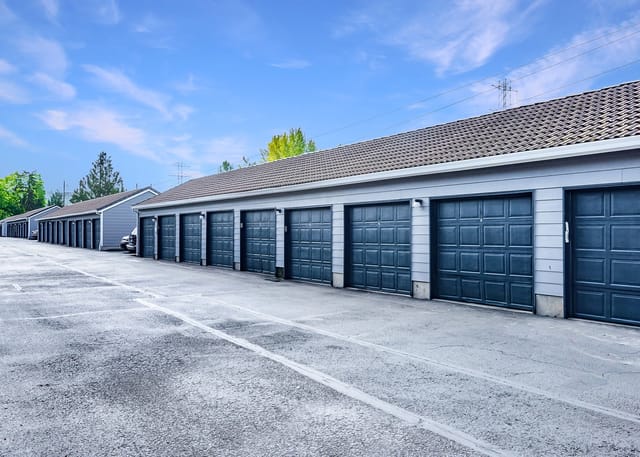 Row of garages with blue doors and grey siding.