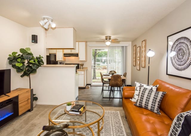 Living room and kitchen area with a leather sofa, coffee table, dining table, and kitchen counter.