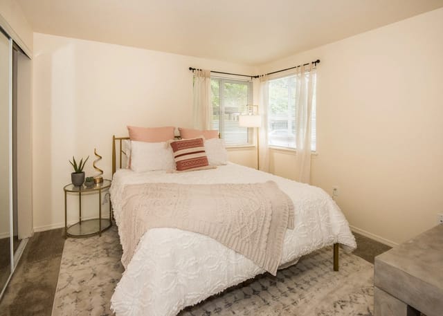 Bedroom with a queen-size bed, bedside table, and a sliding door closet.