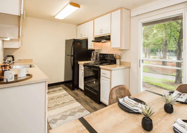 Kitchen with black appliances, white cabinets, and a dining table with place settings.