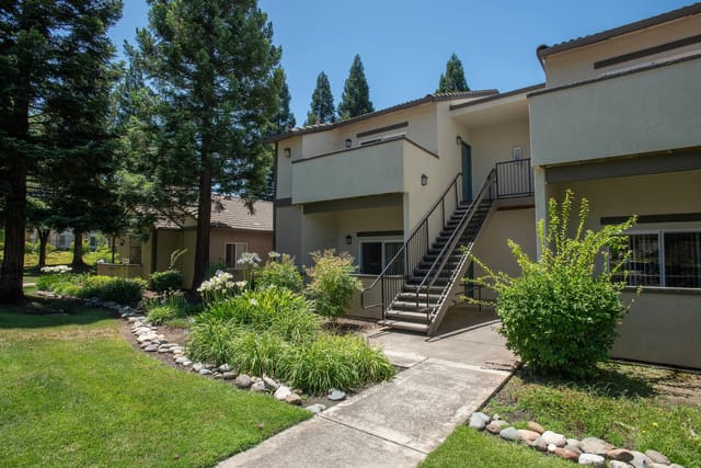 Exterior view of apartment building with stairs, walkways, and landscaping.