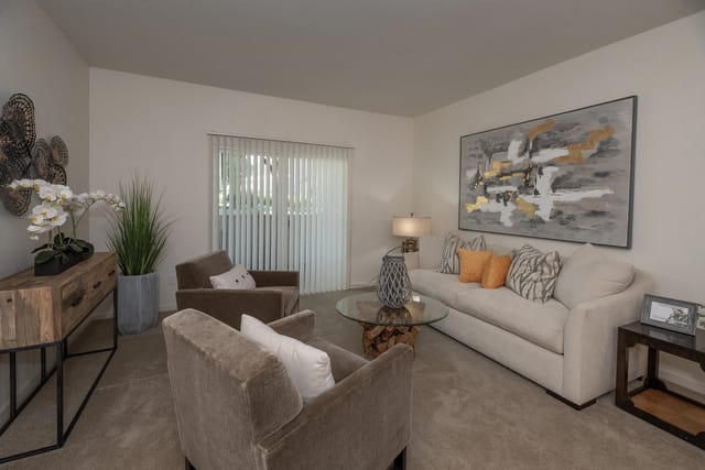 Cozy living room with a couch, two chairs, a coffee table, and a large abstract painting.