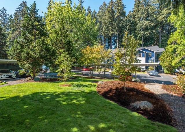 Exterior view of apartment buildings with covered parking and mature trees.