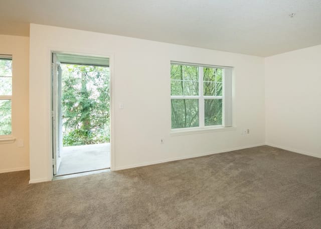 Living room with a door to a patio and a large window overlooking trees