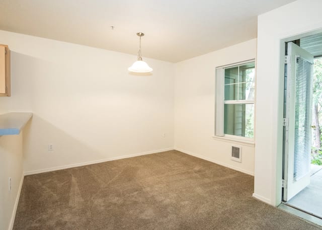 Empty dining room with a window and a door leading to a patio.