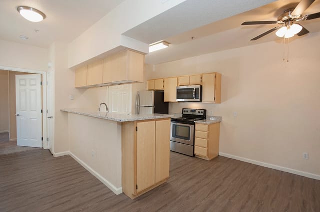Kitchen with light wood cabinets, granite countertops, and stainless steel appliances.