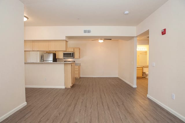 Living room and kitchen area with light wood cabinets, granite countertops, and stainless steel appliances.