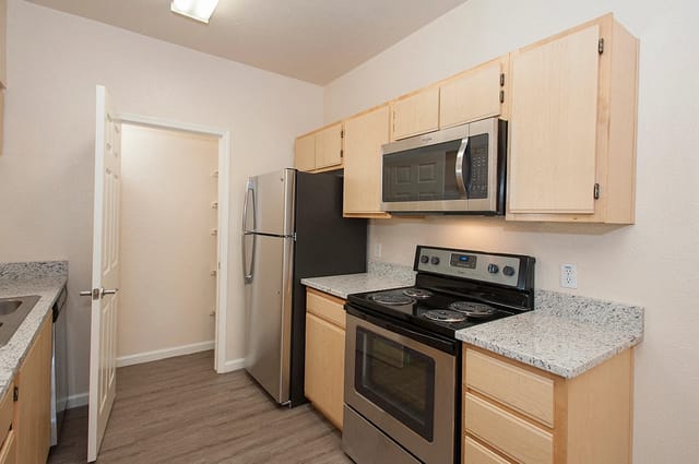 Kitchen with stainless steel appliances, granite countertops, and light wood cabinets.