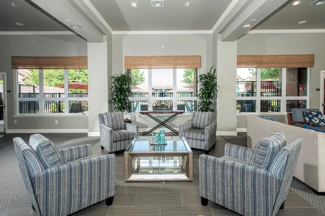Lobby seating area with plush chairs, a glass coffee table, and large windows overlooking the pool and courtyard.