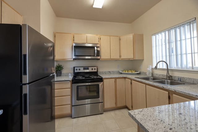 Modern kitchen with stainless steel appliances and light wood cabinets.