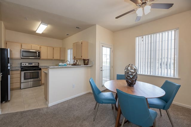 Dining area with table and chairs next to kitchen.