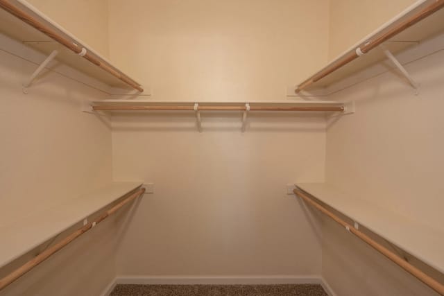 Empty walk-in closet with shelving and hanging rods.