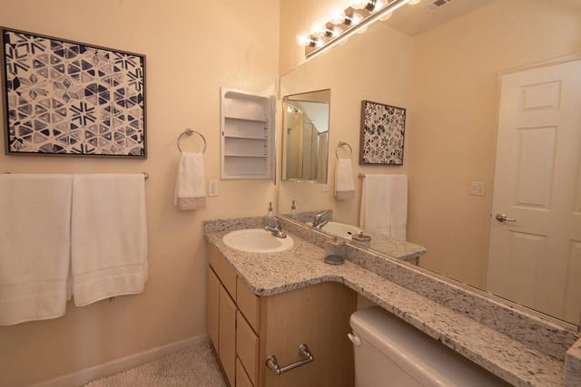 Bathroom with vanity, sink, mirror, towels, and artwork.