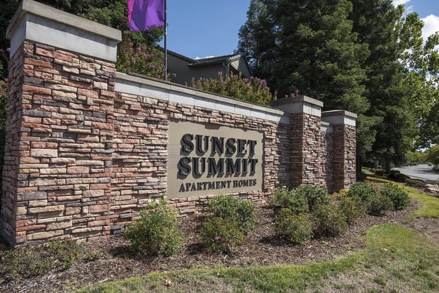 Sunset Summit Apartment Homes monument sign with stone pillars and landscaping.