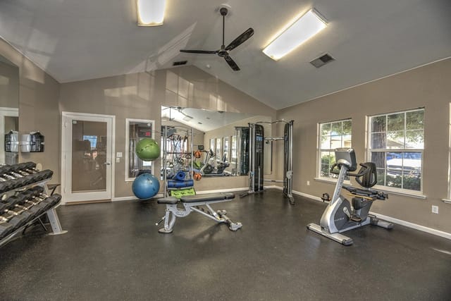 Gym with dumbbells, exercise machines, exercise balls, and a weight bench.