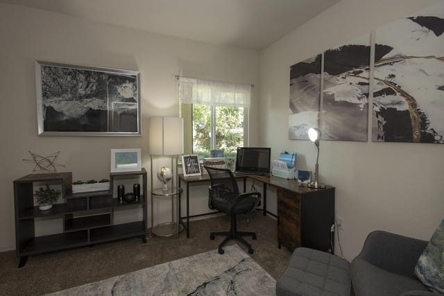Home office setup with L-shaped desk, computer, chair, and artwork.