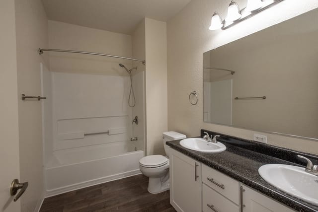 Modern bathroom with a double vanity, toilet, and shower/tub combo.