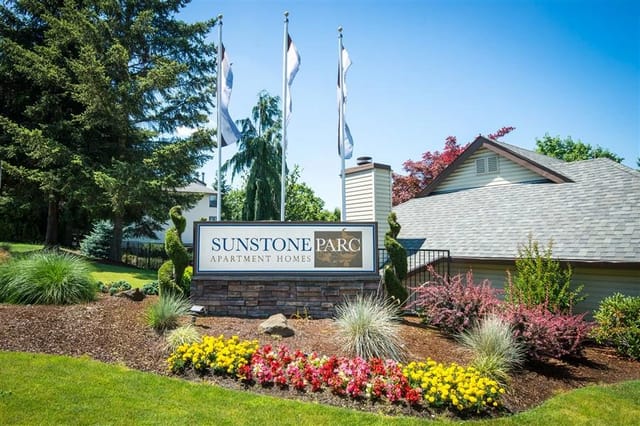 Sunstone Parc Apartment Homes monument sign with landscaping and flags