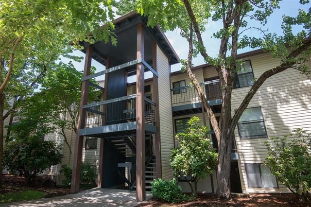 Exterior building with balconies and staircases, surrounded by trees.