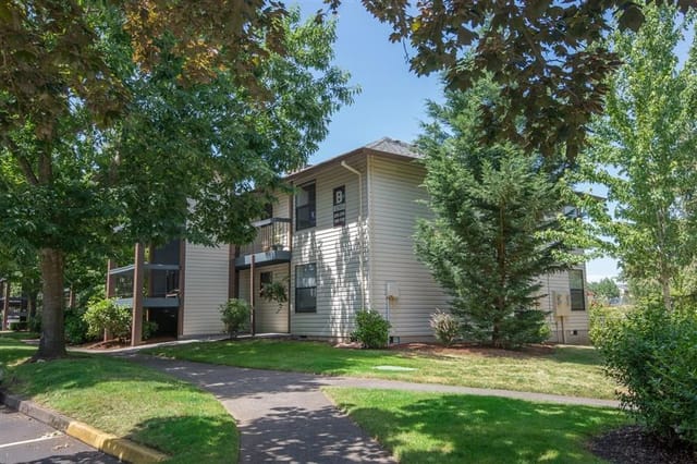 Exterior view of an apartment building with balconies and surrounding trees.
