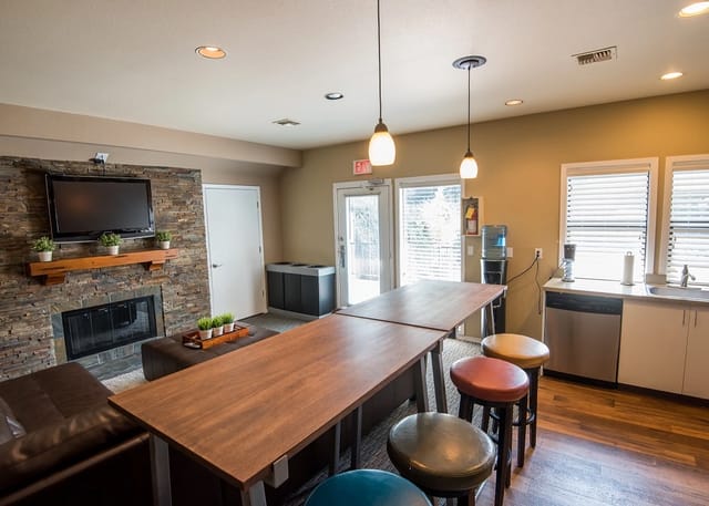 Community lounge area with a fireplace, TV, large table, and kitchen counter.