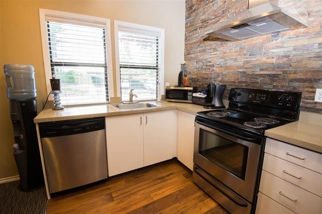 Kitchen with stainless steel appliances, granite countertops, and stone backsplash.
