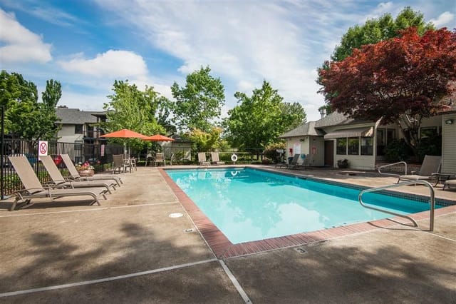 Outdoor swimming pool with lounge chairs and umbrellas.