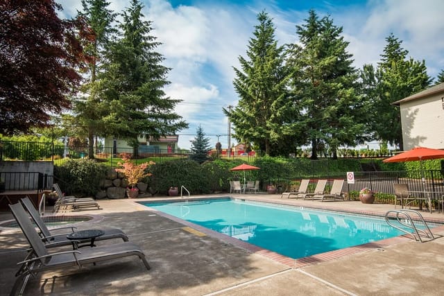 Outdoor swimming pool area with lounge chairs and umbrellas.
