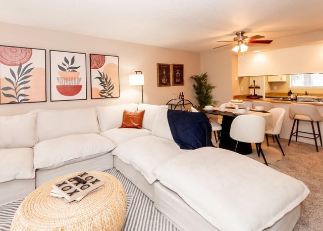 Living room and dining area with sectional couch, dining table, and kitchen counter.