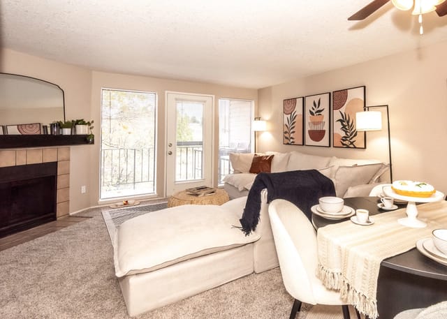 Living room with a fireplace, large sectional sofa, dining table, and balcony access.