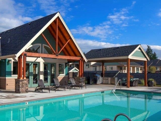 Outdoor swimming pool with lounge chairs and covered seating area with grills.