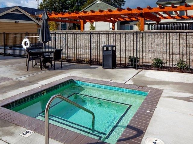 Outdoor spa with seating area under a pergola.