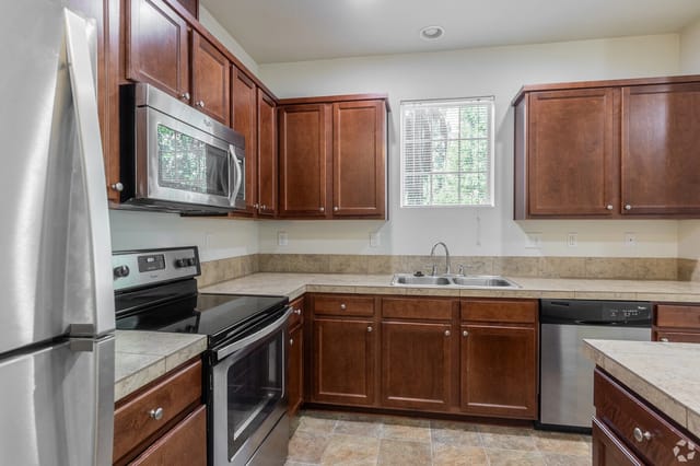 Kitchen with dark wood cabinets, stainless steel appliances including a refrigerator, microwave, oven, and dishwasher.