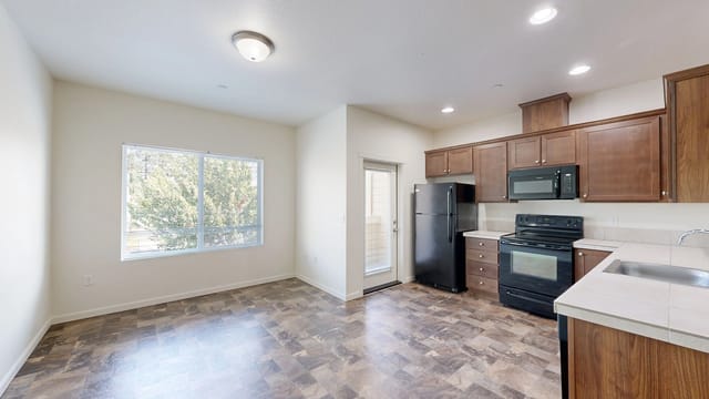 Kitchen with dark wood cabinets, black appliances, and a large window.