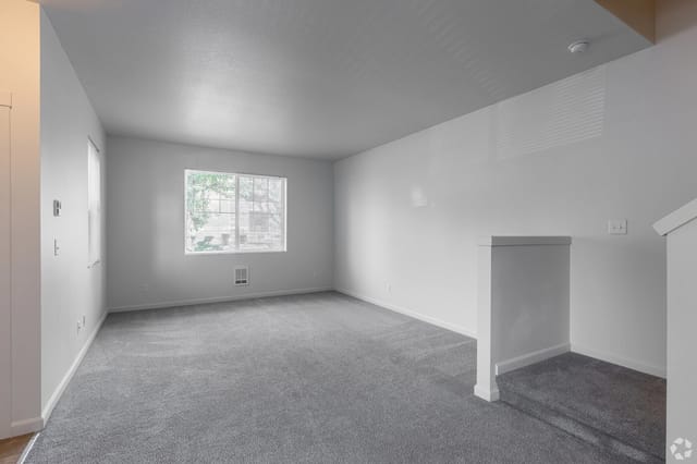 Spacious living room with carpet and a large window.