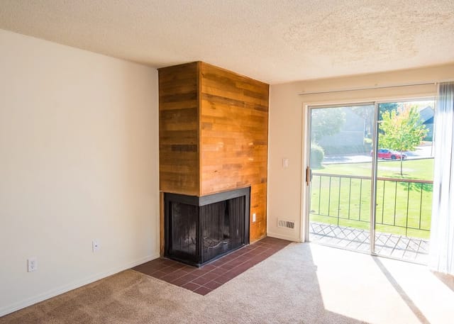 Living room with a wood-paneled fireplace and sliding glass door to a balcony.