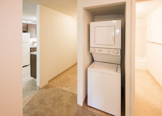 Stacked washer and dryer unit in apartment hallway.