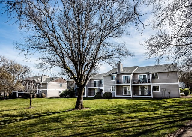 Exterior view of apartment buildings with manicured lawns and trees.