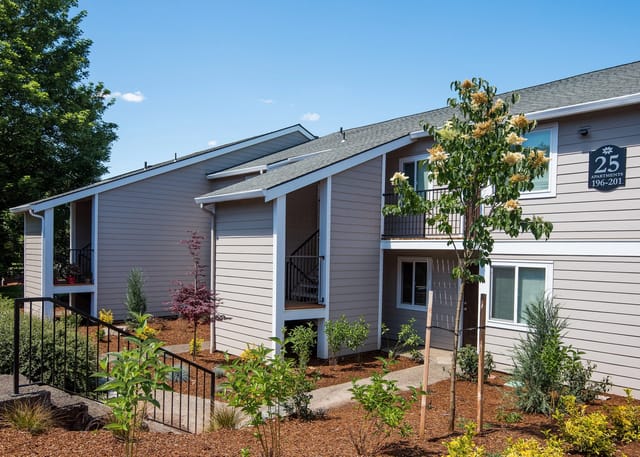 Exterior view of apartment building with beige siding and green landscaping.