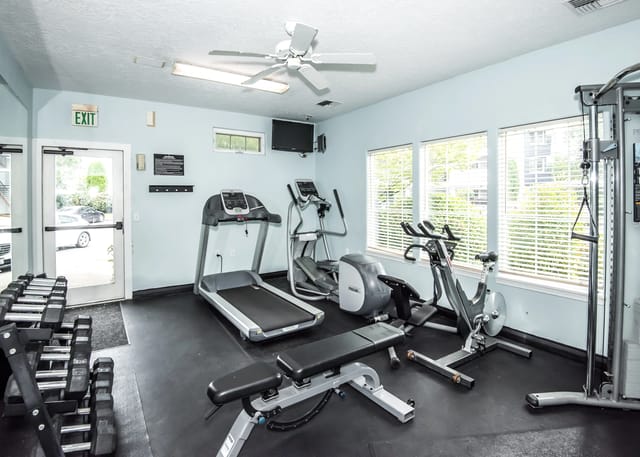 Gym with treadmills, elliptical, stationary bike, weight bench, and dumbbells.