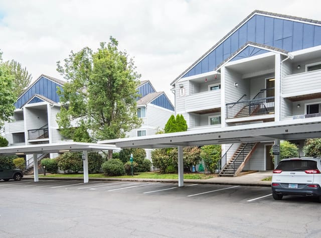 Apartment buildings with covered parking and lush greenery.