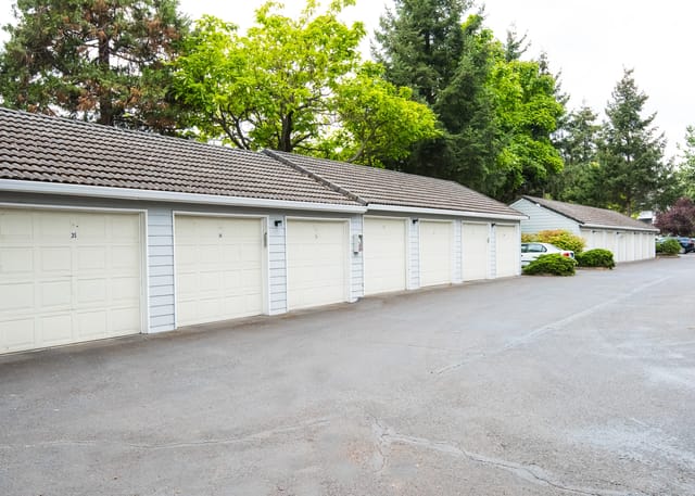 Row of garages with cream-colored doors and numbers on them.