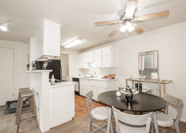 Kitchen and dining area with white cabinets, black appliances, and a round dining table.