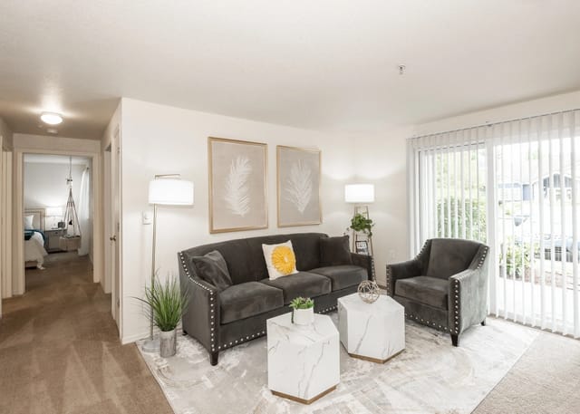 Stylish living room with a dark gray sofa, accent chair, marble coffee tables, and artwork.