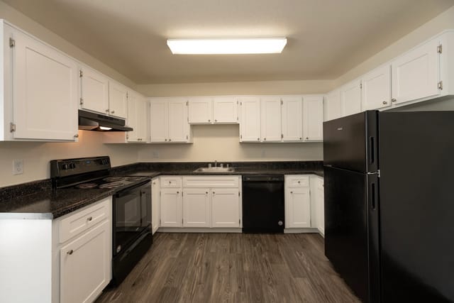 Kitchen with white cabinets, black appliances, and dark countertops.