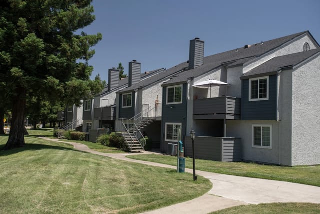 Exterior view of apartment buildings with walkways and manicured lawns.