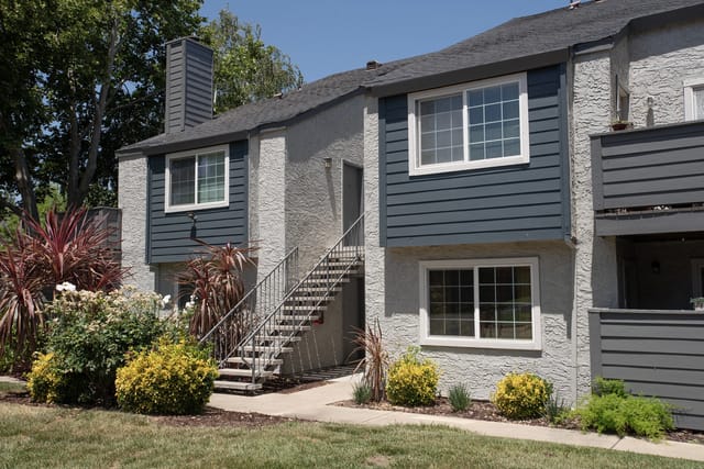 Exterior view of apartment building with stairs and landscaping.