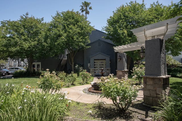 Landscaped courtyard with a fountain and seating area in front of an apartment building.