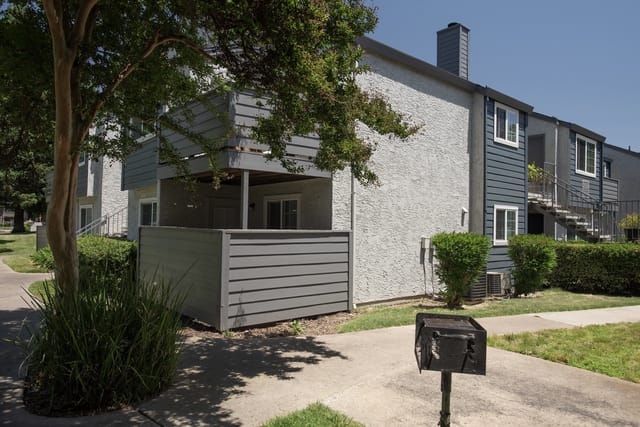 Exterior view of apartment building with balcony and outdoor grill.